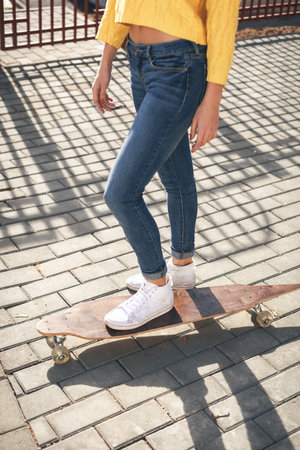 Beautiful young girl standing with a longboard in the afternoon. Skateboarding. Outdoors, lifestyleの写真素材
