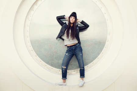Portrait of a beautiful girl hipster. Pretty young woman posing against a wall in the shape of a...