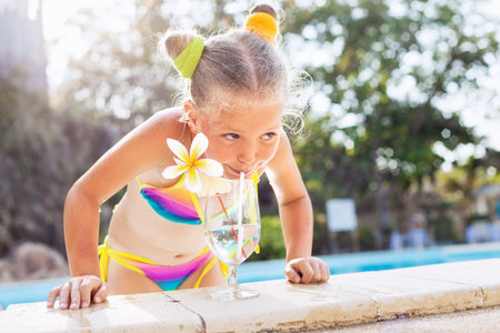 Beauty portrait little girl drinking cocktail in tropical beach pool. Outdoorsの写真素材