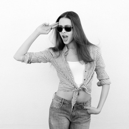 Young woman posing by the wall. Girl saluting. Black and white. Not isolatedの写真素材