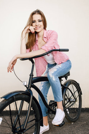 Young hipster girl with black bike looking at camera. Outdoor lifestyle portraitの写真素材