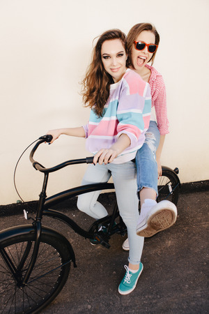 Two funny girls with bicycle having fun. Outdoors, lifestyle.の写真素材