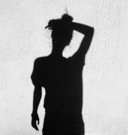 shadow of tired woman wiping forehead around on wall backgroundの写真素材