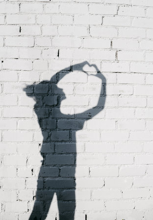 Portrait of a young woman showing a Heart with Her Hands around on the brick wall background.の写真素材