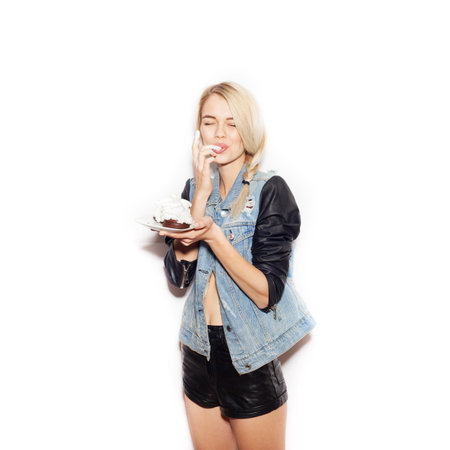 Pretty blonde girl eating chocolate Cake. Indoor lifestyle portrait of woman in sunglasses.  White background, not isolatedの写真素材