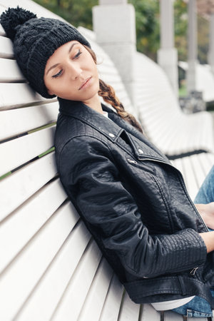 Beautiful young female sitting on the bench park. Outdoor lifestyle portrait of womanの写真素材