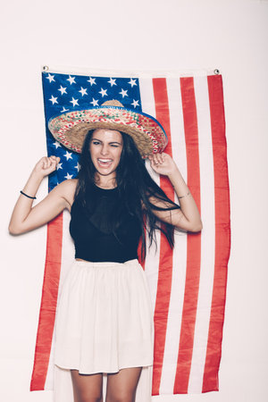 Portrait of a young Latina girl in sambrevo having fun on the background of the American flag. Portrait on white background, not isolatedの写真素材