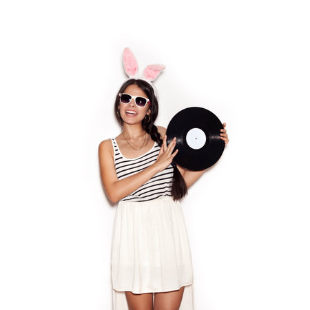 Young teenage girl in pink bunny ears. Sweet woman having fun with musical plate on white background, not isolatedの写真素材