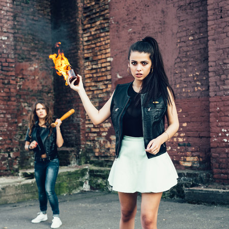 Two Bad fan girls with Molotov cocktail bomb in the street.  Outdoor lifestyle portraitの写真素材