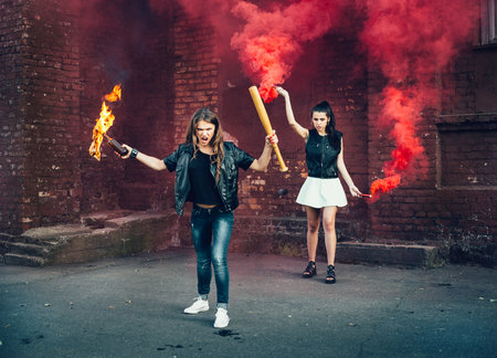 Two women protesters with Molotov cocktail bomb in the street.  Outdoor lifestyle portraitの写真素材