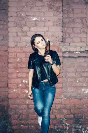 Bad girl lighting up a cigarette from Molotov cocktail bomb in her hand.  Outdoor lifestyle portraitの写真素材