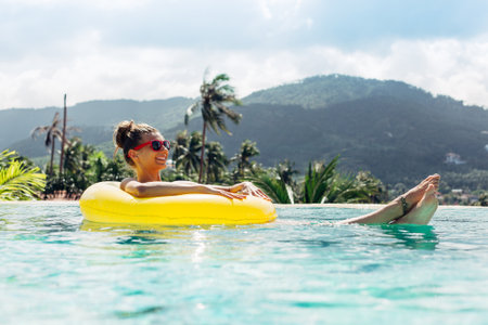 Young pretty fashion woman body posing in summer in pool with clear water lying inner tube and...
