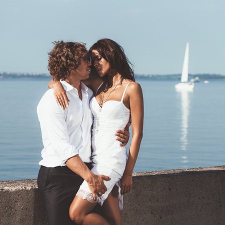 Young couple loving each other. Beautiful man and woman kissing on the waterfront.の写真素材