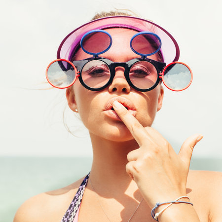 Young blonde girl in sunglasses showing middle finger. Outdoors lifestyle close-up of sexy woman on...