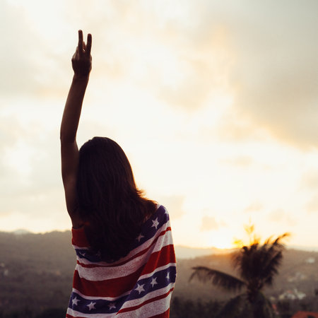 Lovely female model  wrapped in a towel watching the sunset. Beautiful serene relaxing woman in pure happiness and elated enjoyment with arms raised outstretched up. Outdoors lifestyle portraitの写真素材