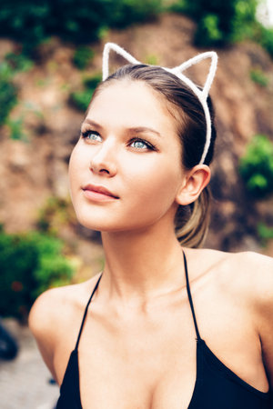 Fashion portrait of young sexy brunette wearing cat ears. Outdoors lifestyle portrait of woman. Bright instagram colors.の写真素材