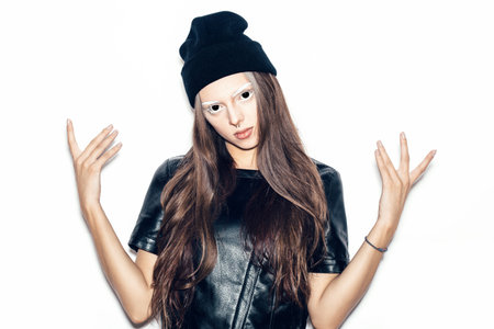 Young beautiful woman in black beanie giving the Rock and Roll sign for a fear or Halloween concept. Toned.  White background, not isolatedの写真素材