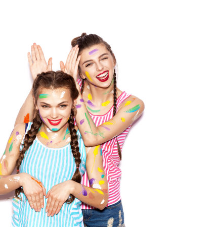Two lovely girl friends having fun. Woman doing bunny ears to her girlfriend. White background not isolatedの写真素材