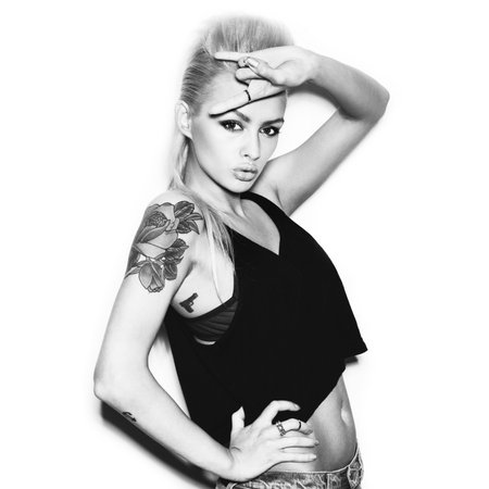 Stylish fashionable blonde girl hipster with tattoo in black clothes. Black and white toned toned. White background, not isolatedの写真素材