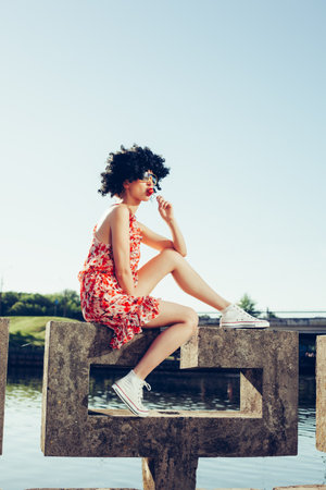 girl with black wig hair sucks lollipop. Outdoors lifestyleの写真素材