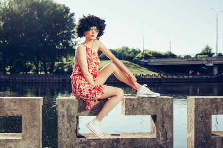 girl with black wig hair sucks lollipop. Outdoors lifestyleの写真素材