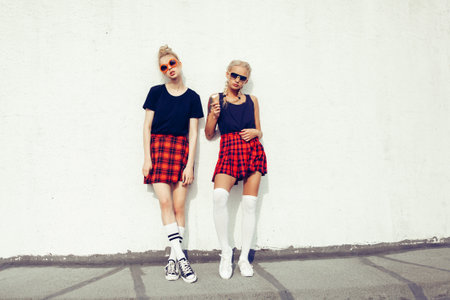 portrait of two pretty hipster blonde sisters  wearing plaid skirt and black T-shirtの写真素材