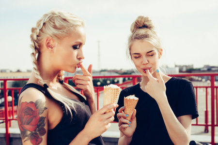Portrait of two sensuality young beautiful girls eating sweet ice-cream. Outdoors lifestyleの写真素材