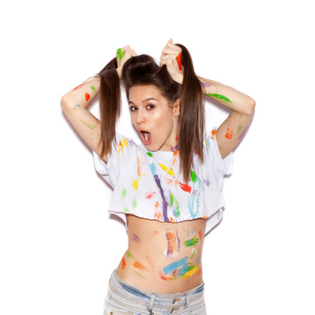 Young cheerful soiled in paint girl with long hair having funの写真素材