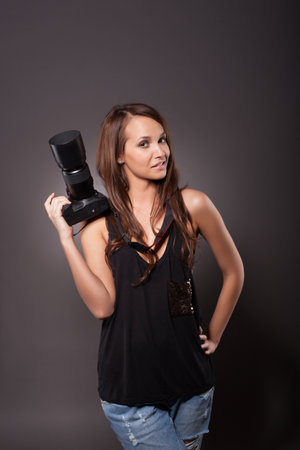 Professional female photographer holding a camera and smilingの写真素材