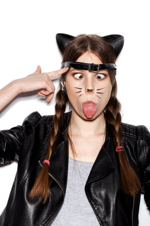 Funny girl represents as small cat.  Woman  with bright makeup hairstyle of girl with leather cat ears and braids having fun. On white background not isolatedの写真素材