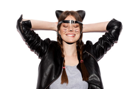 Funny girl represents as small cat.  Woman  with bright makeup hairstyle of girl with leather cat ears having fun. On white background not isolatedの写真素材