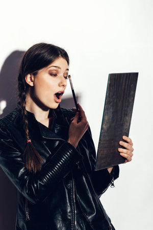 Beauty woman applying makeup. Beautiful girl looking in the mirror and applying cosmetic with a big brush. White background not isolatedの写真素材