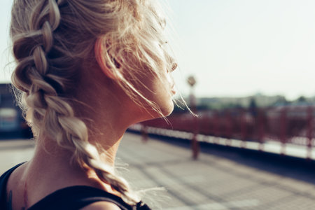 Young pretty girl with braided pigtails. Soft sunny color outdoors portrait.の写真素材