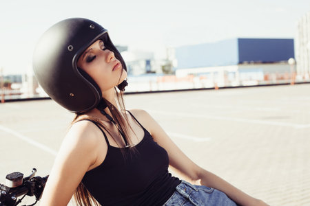 Biker girl in helmet sitting on vintage custom motorcycle. Outdoor lifestyle portraitの写真素材
