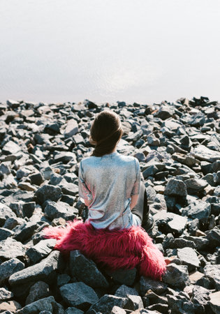 Beautiful young woman outdoors portrait near the lake. Brunette girl looking at the sea, back to the cameraの写真素材