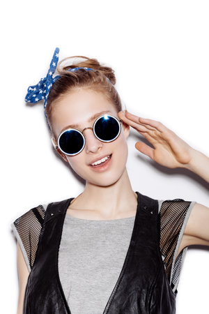 Fashion portrait of beautiful girl wearing sunglasses. Close-up of cute woman smiling and saluting on white background not isolatedの写真素材