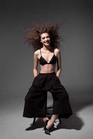 Fashion portrait of young sexy woman with hairstyle posing on grey backgroundの写真素材