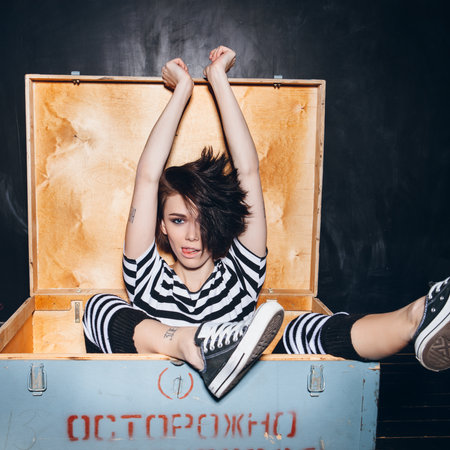 Girl wearing striped pajamas sitting in wooden boxの写真素材