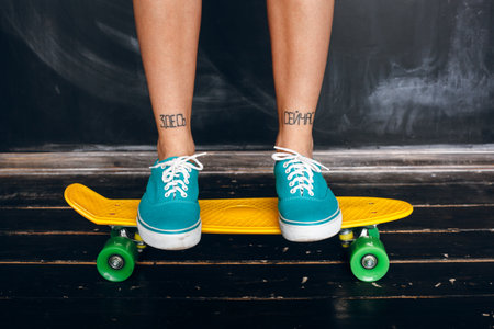 legs of young girl standing on skateboard.の写真素材