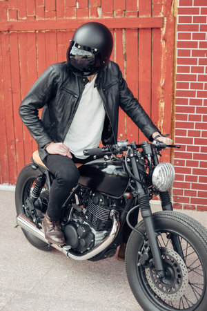 Biker sitting on vintage custom motorcycle. Outdoor lifestyle portraitの写真素材