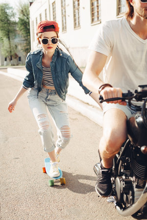 Group of friends skating and cycling in an urban area - Cheerful teenagers having fun outdoors. Young man and woman riding on a sunny day.の写真素材