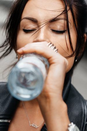 Portrait of young brunette woman drinking water from the bottleの写真素材