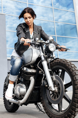 Biker girl in a leather jacket on a vintage custom motorcycle