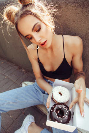 Portrait of cute young girl holding box of donutsの写真素材