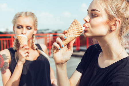Portrait of two sensuality young beautiful girls eating sweet ice-cream. Outdoors lifestyle
