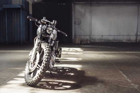 Vintage motorcycle standing in a dark building in the rays of sunlight. Front viewの写真素材