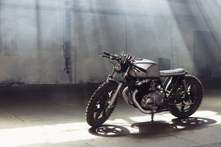 Vintage motorcycle standing in a dark building in the rays of sunlight