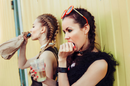 Young women drinking from a paper bag in the street. Outdoor girls portrait, Fashion models