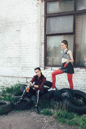 Two young girls relaxing on a sunny day. Fashionable style, hairstyle with braids. Outdoors lifestyle toned portraitの写真素材