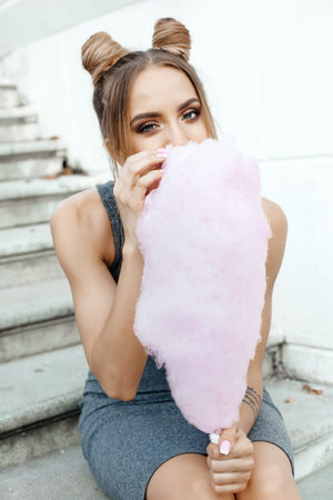 Girl eating a cotton candy. Outdoors lifestyle portrait of woman having funの写真素材
